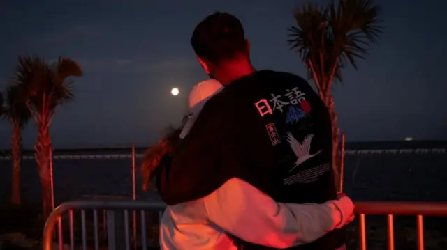 A couple looks at the Moon after the launch of the next-generation moon rocket