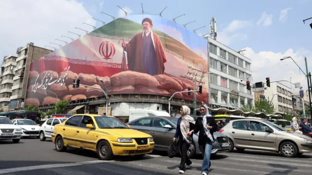 Iranians walk past a billboard of Supreme Leader Ayatollah Mojtaba Khamenei on a street in Tehran on Monday