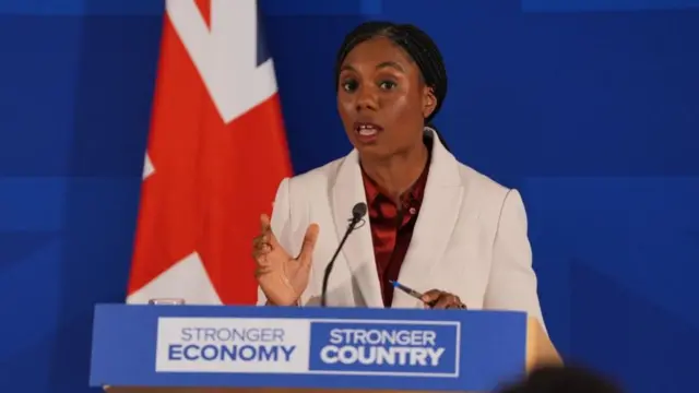 Kemi Badenoch stands at a podium