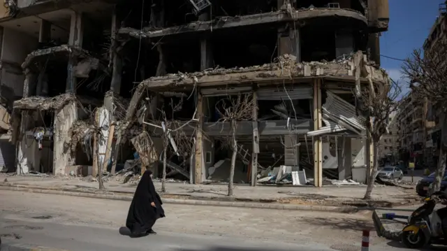 A woman walks past damaged buildings amid a 10-day ceasefire between Lebanon and Israel, in the southern suburbs of Beirut, Lebanon, April 20, 2026