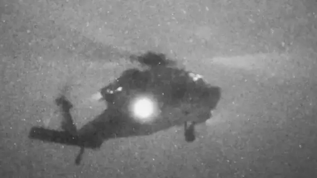 A grainy image og a helicopter through a black and white night vision lens.