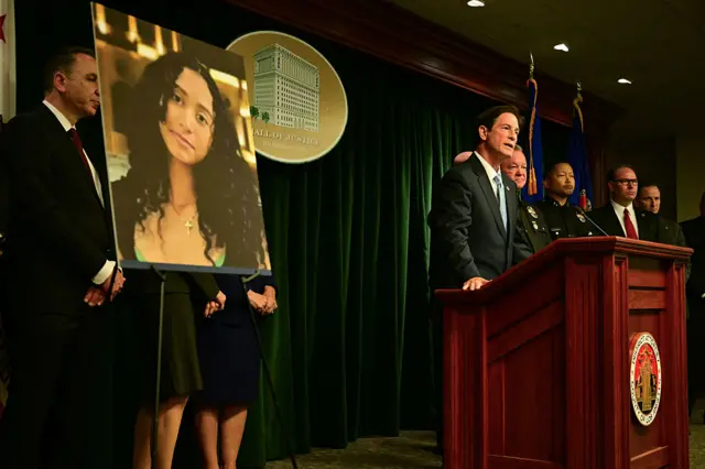 Law enforcement officials stand behind a lectern as a large picture of murder victim Celeste Rivas Hernandez is displayed