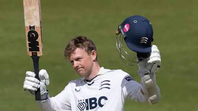 Sam Robson raising his bat and helmet for Middlesex after scoring a century.