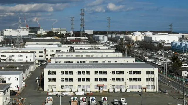 Fukushima Daiichi  nuclear plant. Several white builsings are located next to a car park.