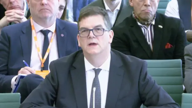 Former top Foreign Office civil servant Sir Olly Robbins wearing black rectangular glasses, dark suit. white shirt and dark tie