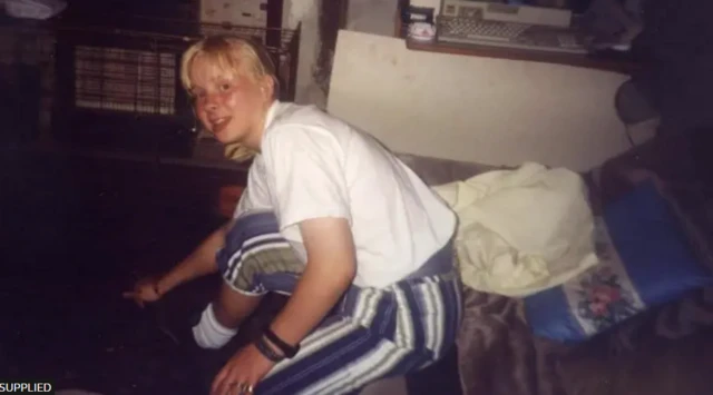 A young woman looks at the camera while sitting on a sofa