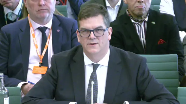 Olly Robbins speaking to MPs on the Foreign Affairs Committee, he is wearing a dark suit and tie