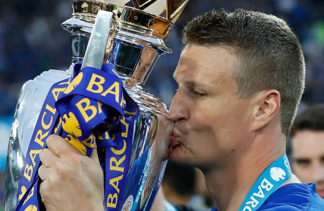Former Leicester player Robert Huth kissing the Premier League trophy
