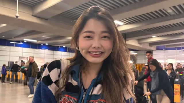Anny who is standing in front of the ticket barriers inside Tottenham Court Road station