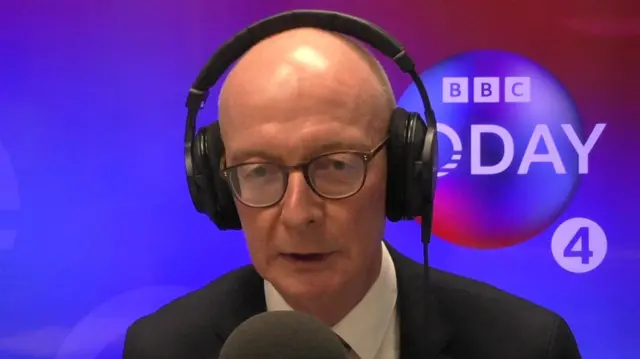 Pat McFadden speaking into microphone with headphones on in Today studio