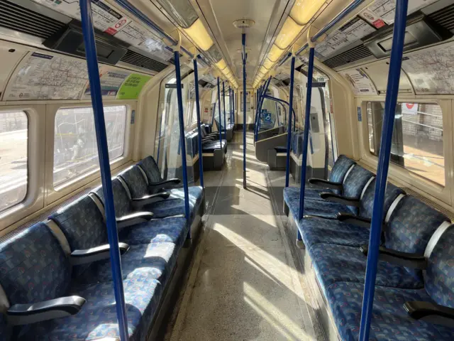 The interior of a Northern line Tube carriage, with blue seats and bars and totally empty with no passengers