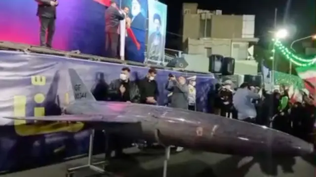 people standing on a city street in Iran near a large drone on display