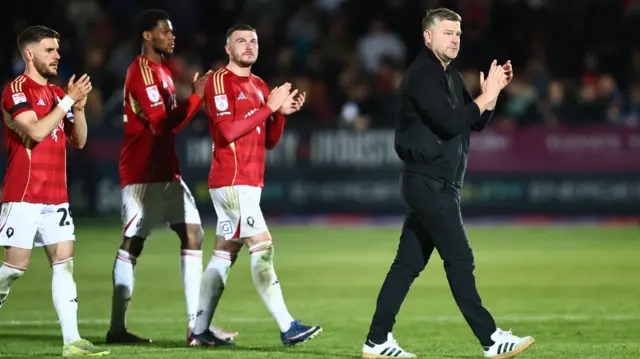 Karl Robinson applauds the fans with his players after the game