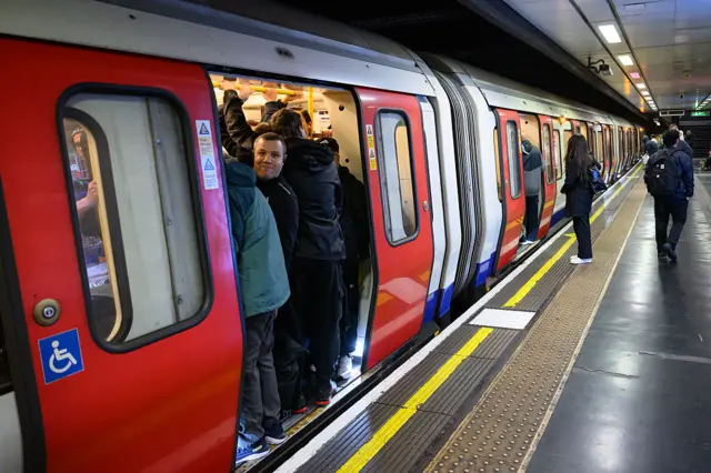 Commuters squeeze into busy train carriages inside at Tube station