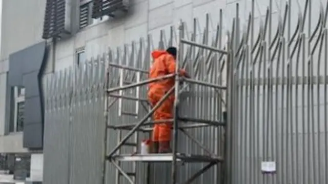 Man in orange overalls carrying out repairs to the outside of the Scottish Parliament building