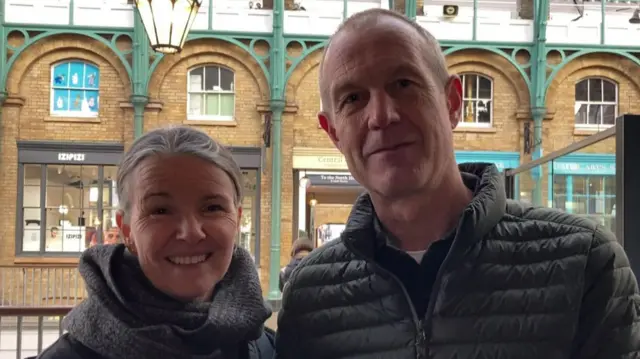 Woman and man pose for a picture wearing warn jackets.