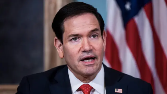 US Secretary of State Marco Rubio with an American flag behind him