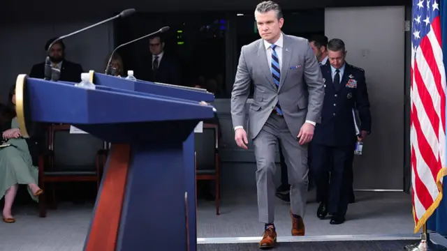 Pete Hegseth walks up to the podium