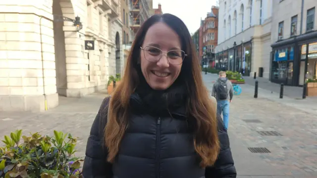 Woman with long brown hair and glasses stands in Covent Garden