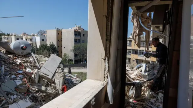 A man checks a book that was found among rubble as he cleans an apartment in a building damaged by an Israeli strike, amid a temporary ceasefire between Lebanon and Israel, in Tyre, April 23, 2026