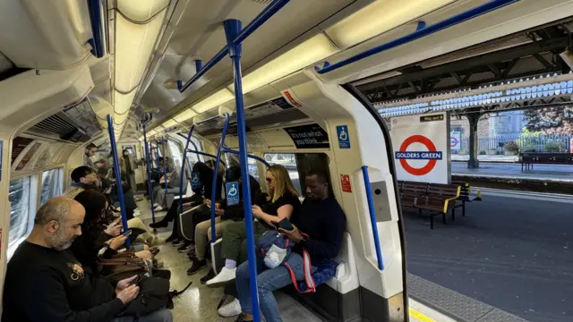 People on board a Tube train while it is stopped at Golders Green station
