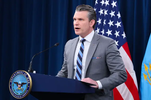 Pete Hegseth speaks behind a podium