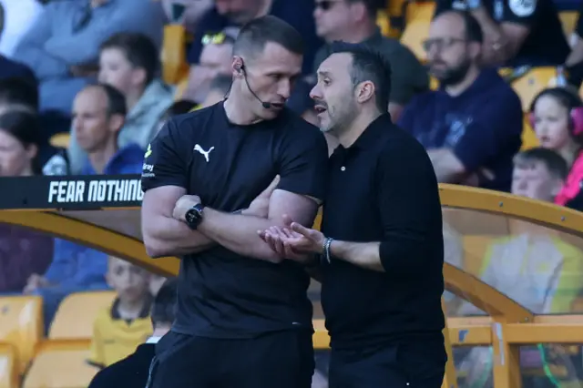 Tottenham Hotspur's Italian head coach Roberto De Zerbi (R) talks with the fourth official