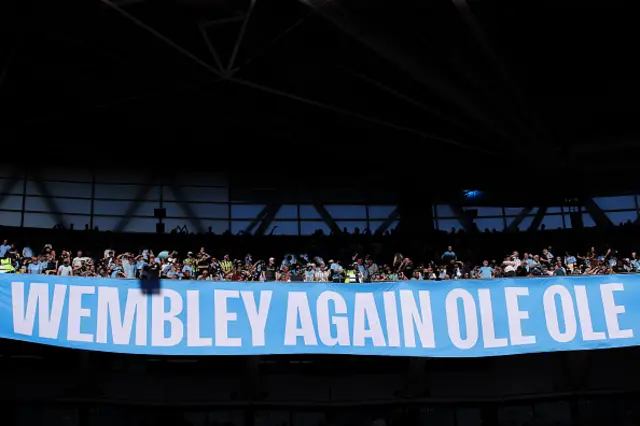 A banner reading 'Wembley Again Ole Ole' is unveiled b