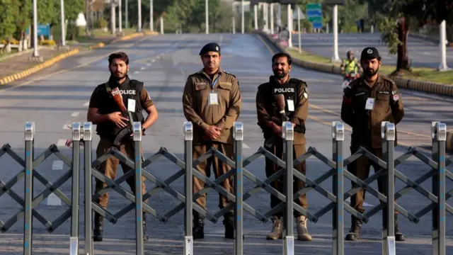 Four police officers stand in a line in the middle of the road
