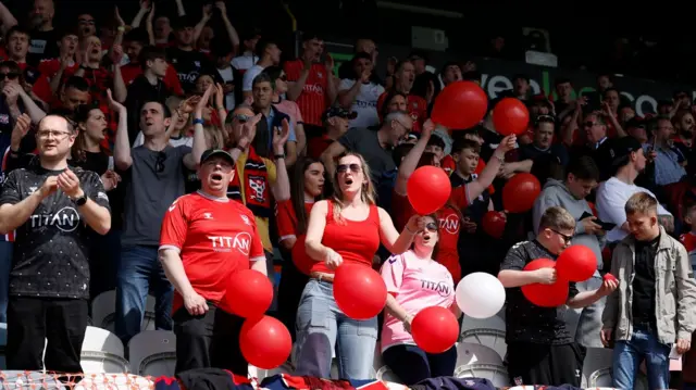 York fans hold red and white balloons at Spotland