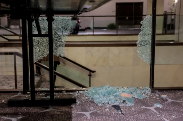Glass shards rests at the bottom of what used to be a glass panel lining a set of internal steps inside a hotel