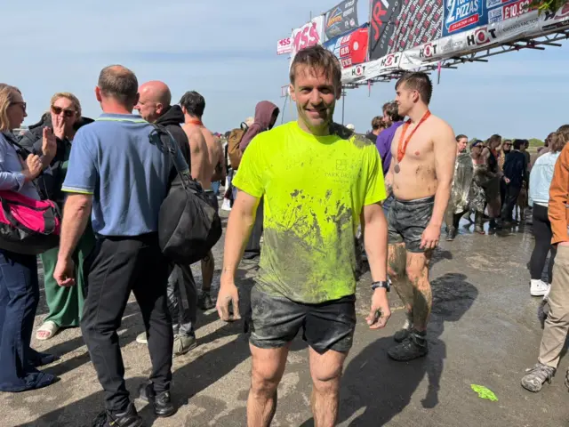 A man stands covered in mud