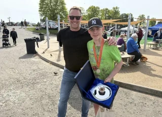 A man and a teenage boy smile at the camera