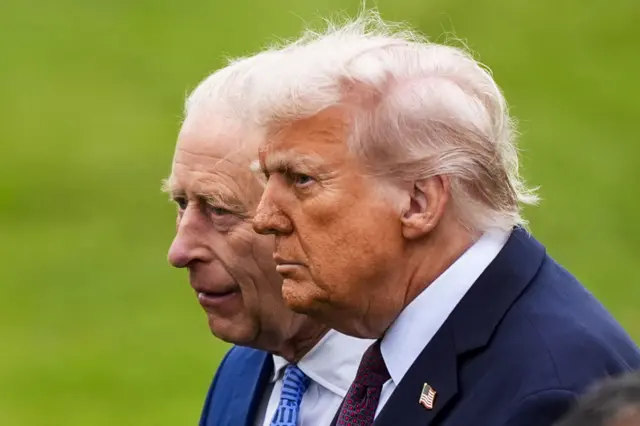 King Charles and Donald Trump standing next to each other while walking along the lawn of Windsor Castle