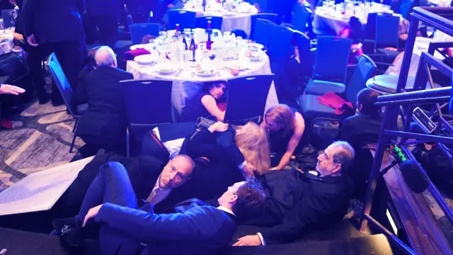 Guests duck under the table after shots appeared to ring out