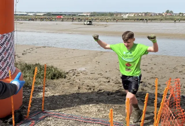 A young man wearing a green top crosses the finish line