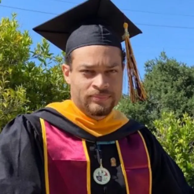 Image shows suspect Cole Allen wearing mortar board and graduation robes