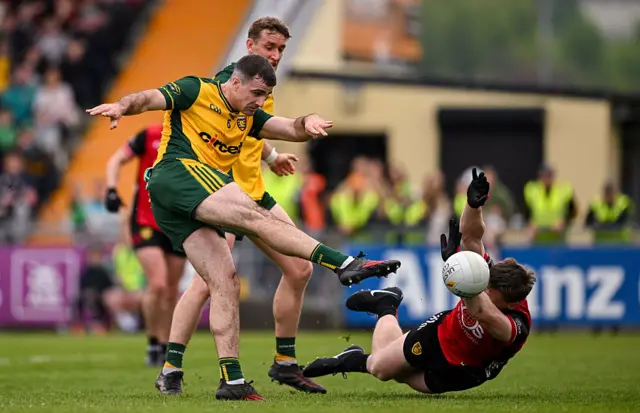 Caolan McGonagle of Donegal shoots to score his side's first goal despite the attention of Odhran Murdock of Down