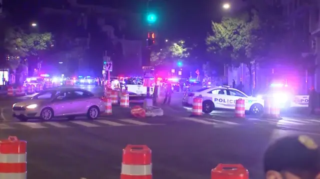 city street blockaded by police cars with their lights flashing