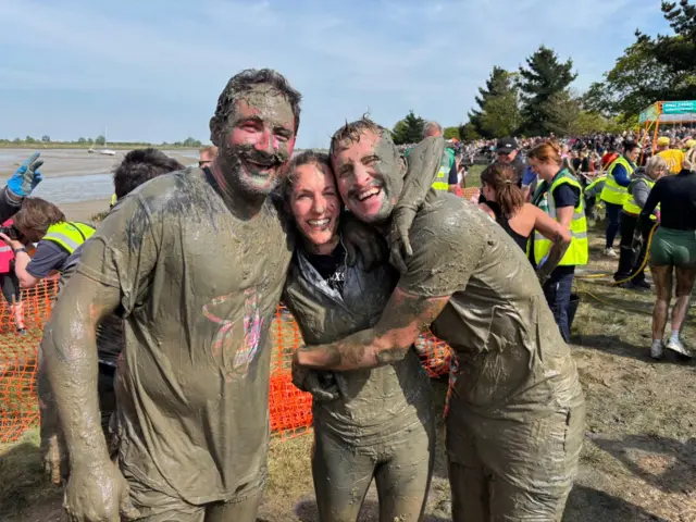 People covered in mud hug each other