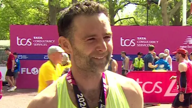 Harry Judd wearing his running gear and a marathon medal