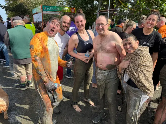 People covered in mud hug each other