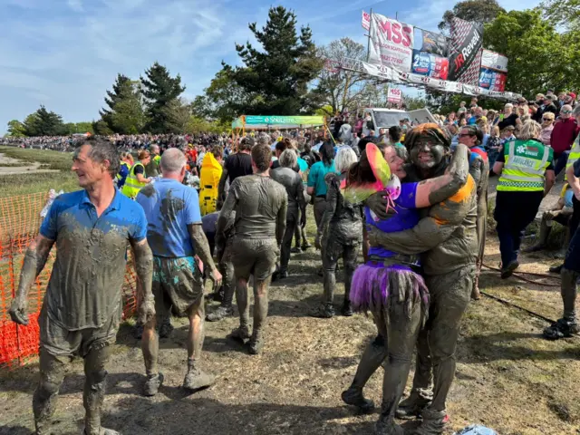People covered in mud hug each other