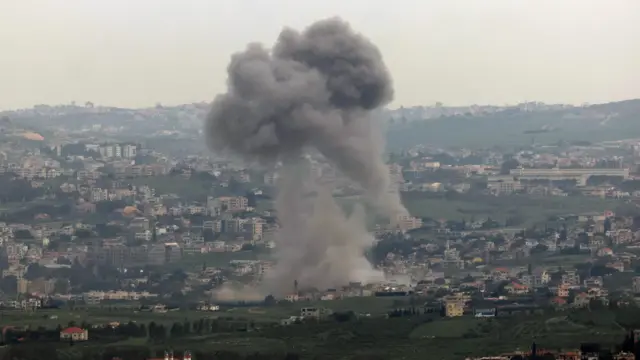 A wide shot of smoke rising from across the Israel border into southern Lebanon