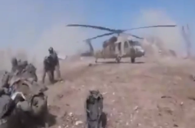 A screengrab from the video showing the helicopter landing before the explosion, people are stood nearby.