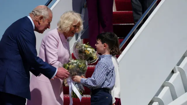 Britain's King Charles and Queen Camilla receive bunches of flowers from two children