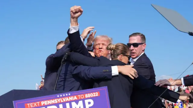 Former president Donald Trump raises his arm with blood on his face during a campaign rally for former President Donald Trump at Butler Farm Show Inc. on Saturday, July 13, 2024