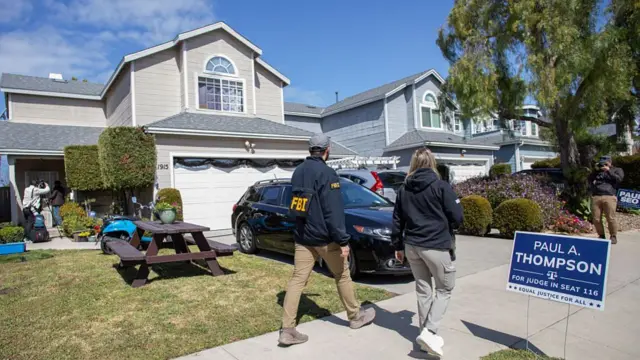 Two FBI agents walk past a two-level house believed to be linked to the suspect in the White House Correspondents' Dinner shooting in Torrance, California