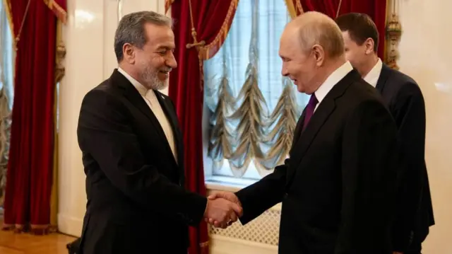 Araghchi and Putin shaking hands.