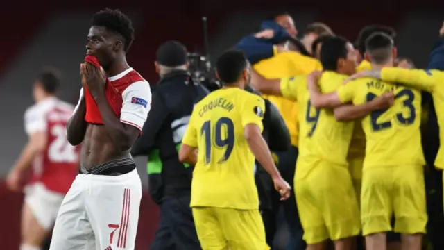 Arsenal's Bukayo Saka looks dejected as Villarreal players celebrate winning their Europa League semi-final in 2021